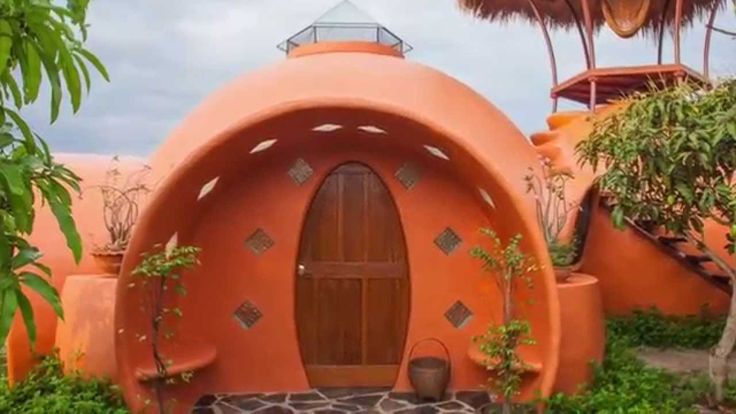 an orange building with a wooden door surrounded by plants