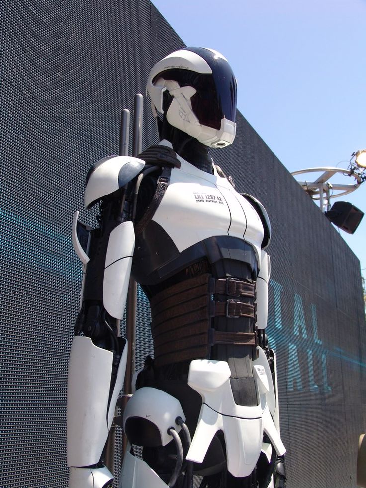 a white and black robot standing in front of a building