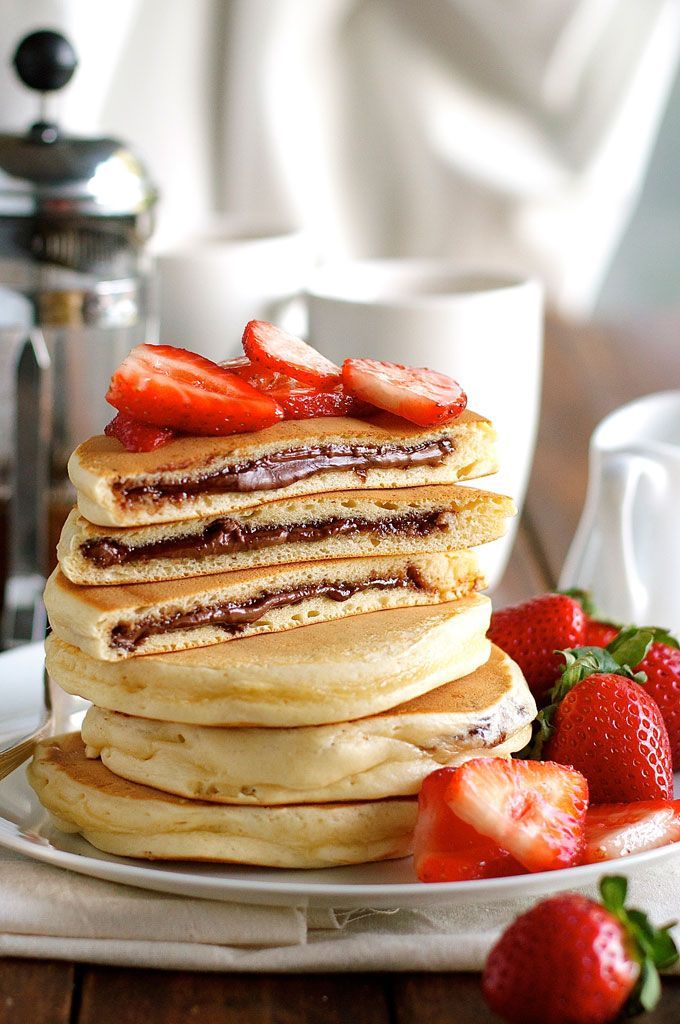 a stack of pancakes sitting on top of a white plate with strawberries next to it