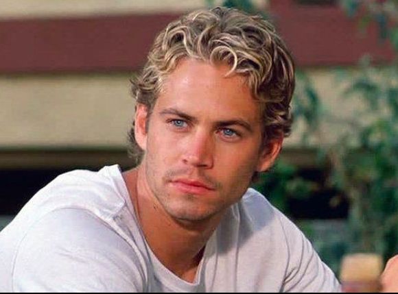 a man with blonde hair and blue eyes is leaning on a table looking at the camera