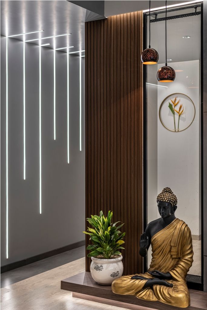 a buddha statue sitting next to a plant in a room with wooden paneled walls