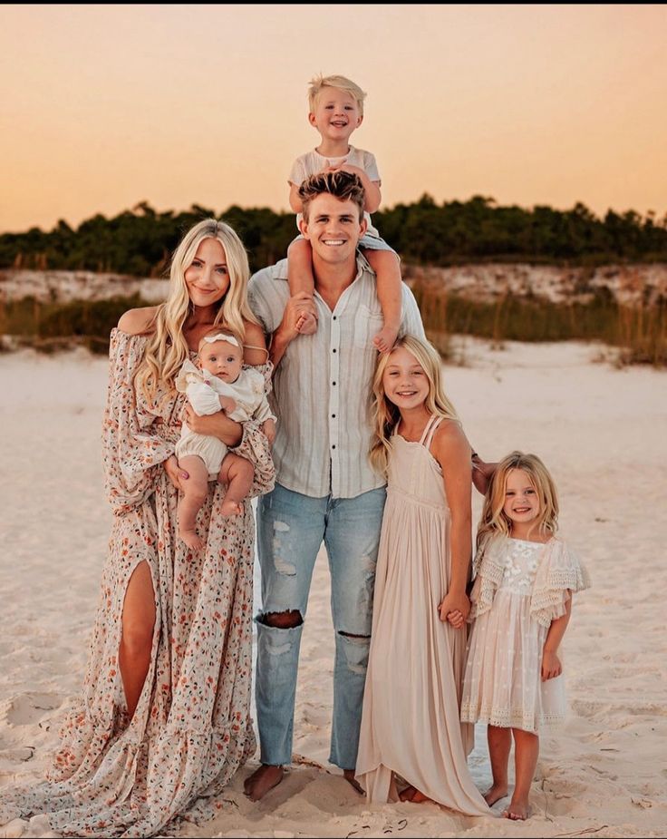 a family poses for a photo on the beach at sunset with their two children and one adult