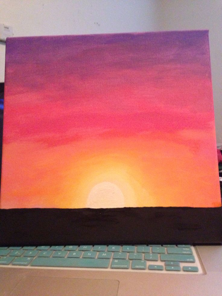 a laptop computer sitting on top of a desk with a sunset painted on the screen