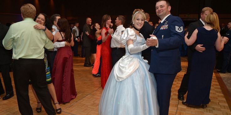 two people dressed in formal wear dancing on a dance floor with other people standing around