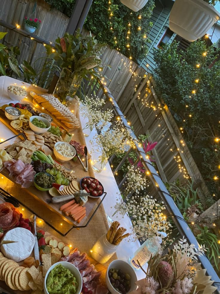 a table filled with lots of food on top of a wooden table covered in lights