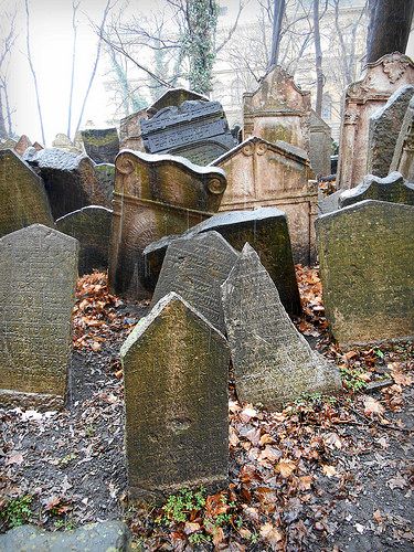 an old cemetery with headstones and trees in the backgrouds, surrounded by fallen leaves