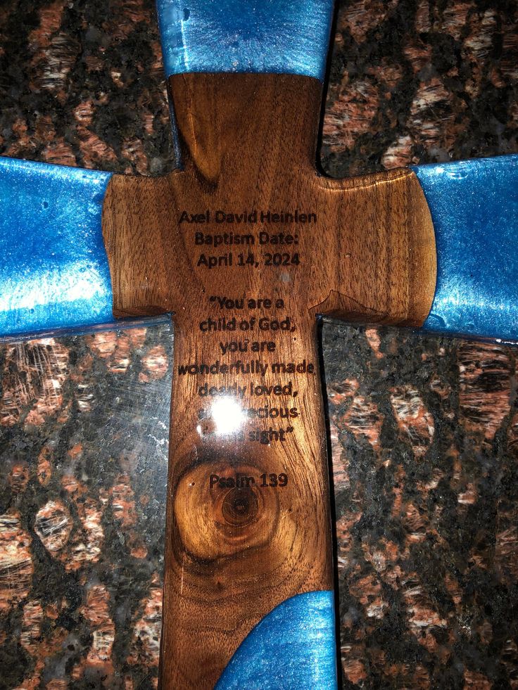 a wooden cross with blue ribbon around it on top of a granite flooring area