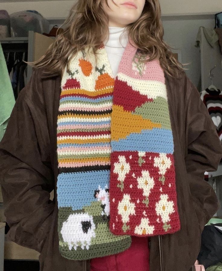 a woman wearing a multicolored crocheted scarf with sheeps on it