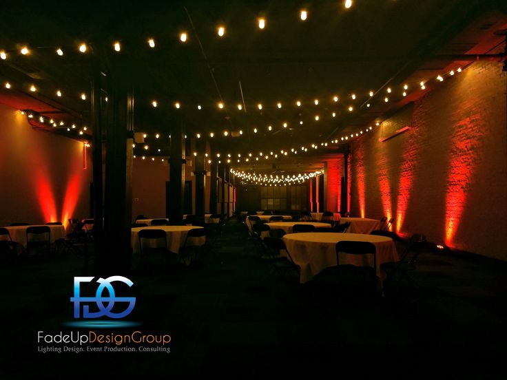 a dimly lit room with white tables and red lights on the walls, along with round tablecloths