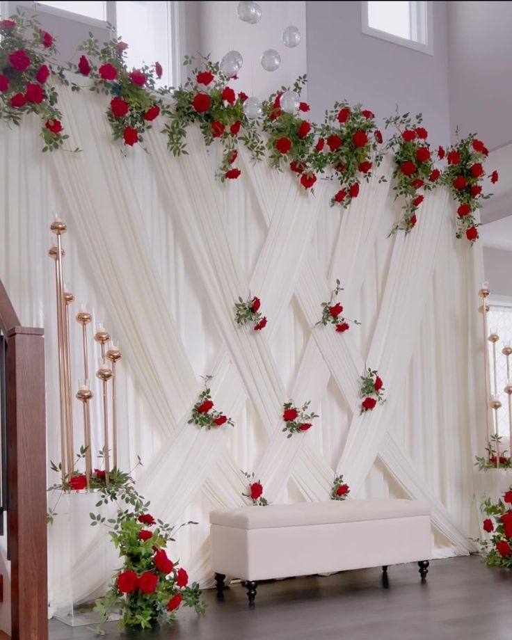 a white couch sitting in front of a wall with red roses on it's side