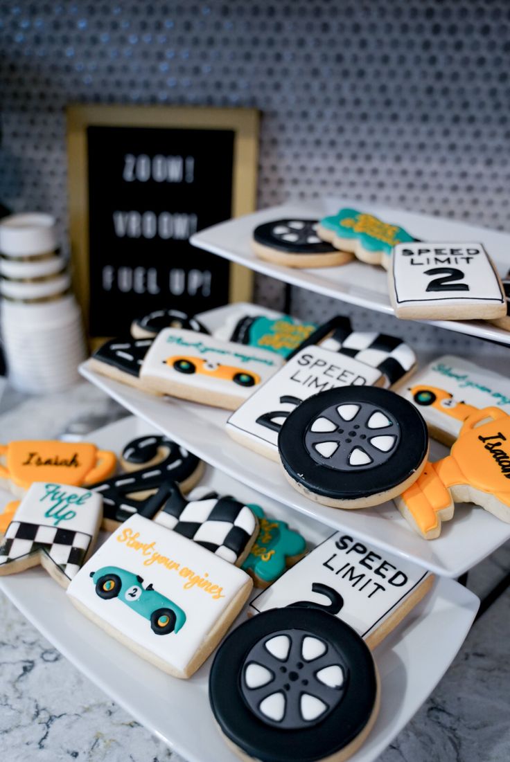 decorated cookies are displayed on three tiers in the shape of race cars and tires