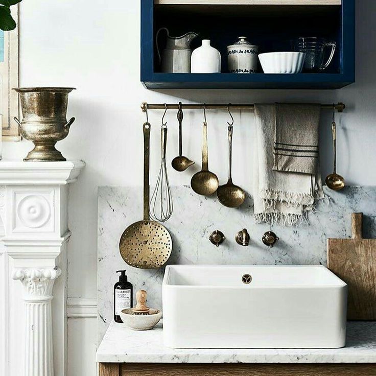 a white sink sitting under a shelf filled with pots and pans on top of a counter