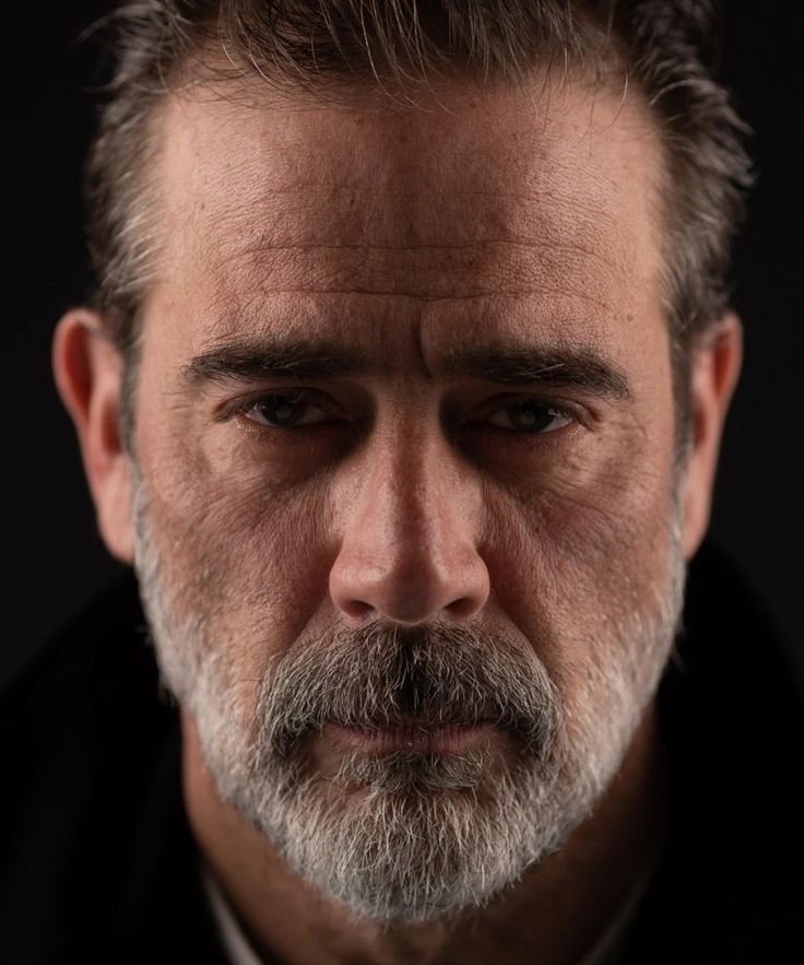 a close up of a man with a beard wearing a black shirt and white tie