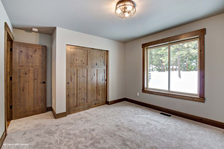 an empty room with wooden doors and carpeted flooring in front of a window