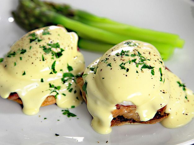 two eggs benedicts on a plate with asparagus