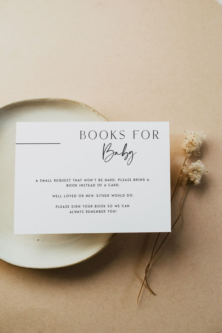 a book for baby card sitting on top of a plate next to a flower bouquet