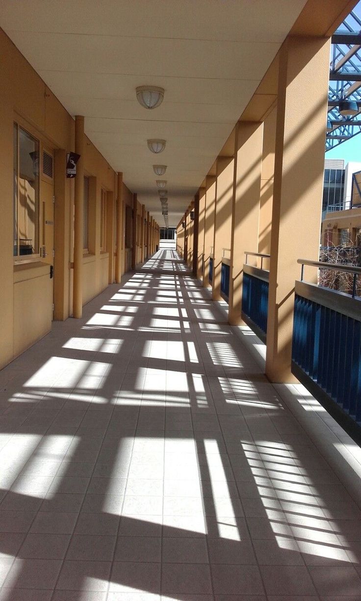 the sun is shining down on an empty hallway with long columns and tiled flooring