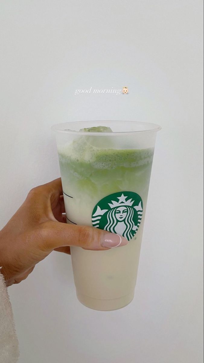 someone holding up a starbucks drink with green liquid in it's cup and ice cream on top