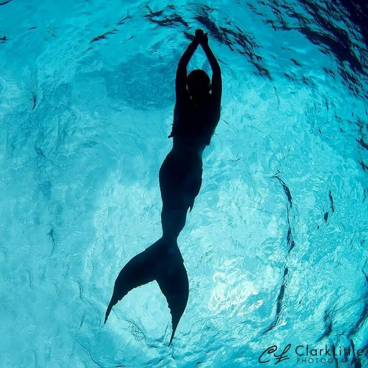 a woman is silhouetted in the water with her arms up and hands behind her back