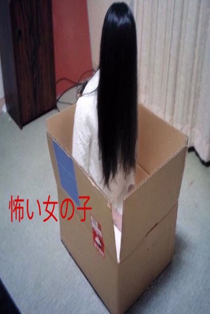 a woman sitting in a cardboard box with long black hair