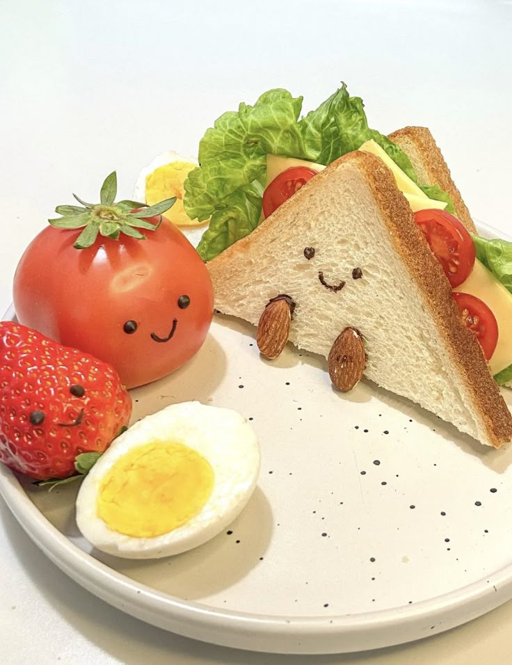 a plate that has some food on it with an egg, tomato and bread in the shape of a face