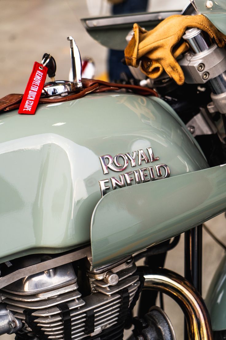 the royal enfield motorcycle is parked on the side of the road with gloves hanging from it's handlebars