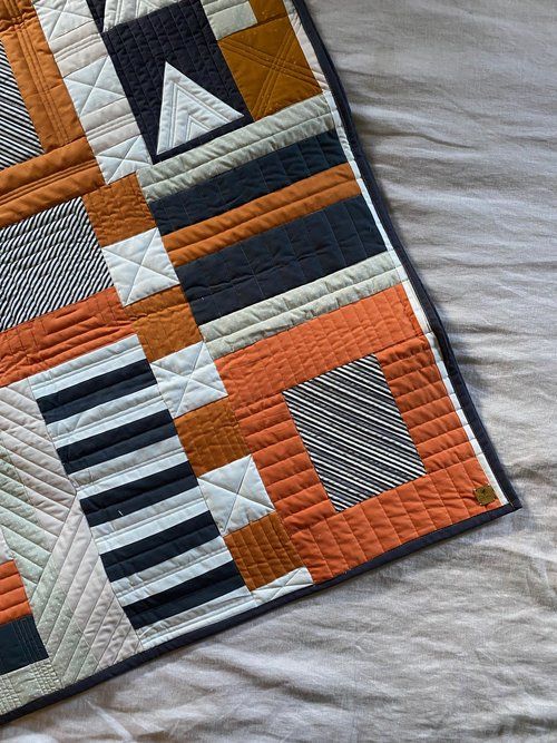 an orange and black quilt on a bed