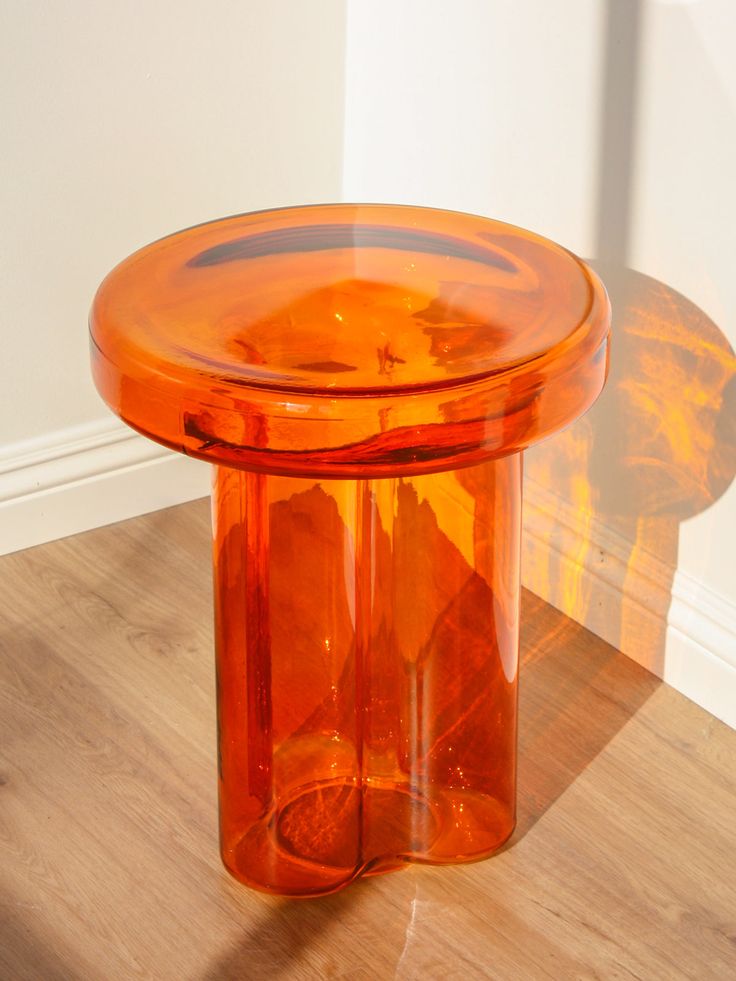 an orange glass table sitting on top of a wooden floor