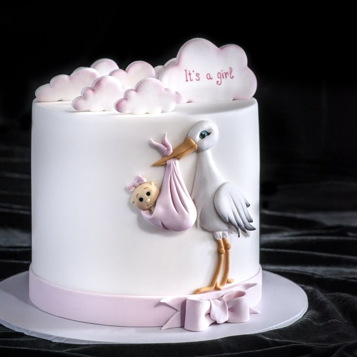 a baby shower cake with a stork holding a teddy bear and it's a girl