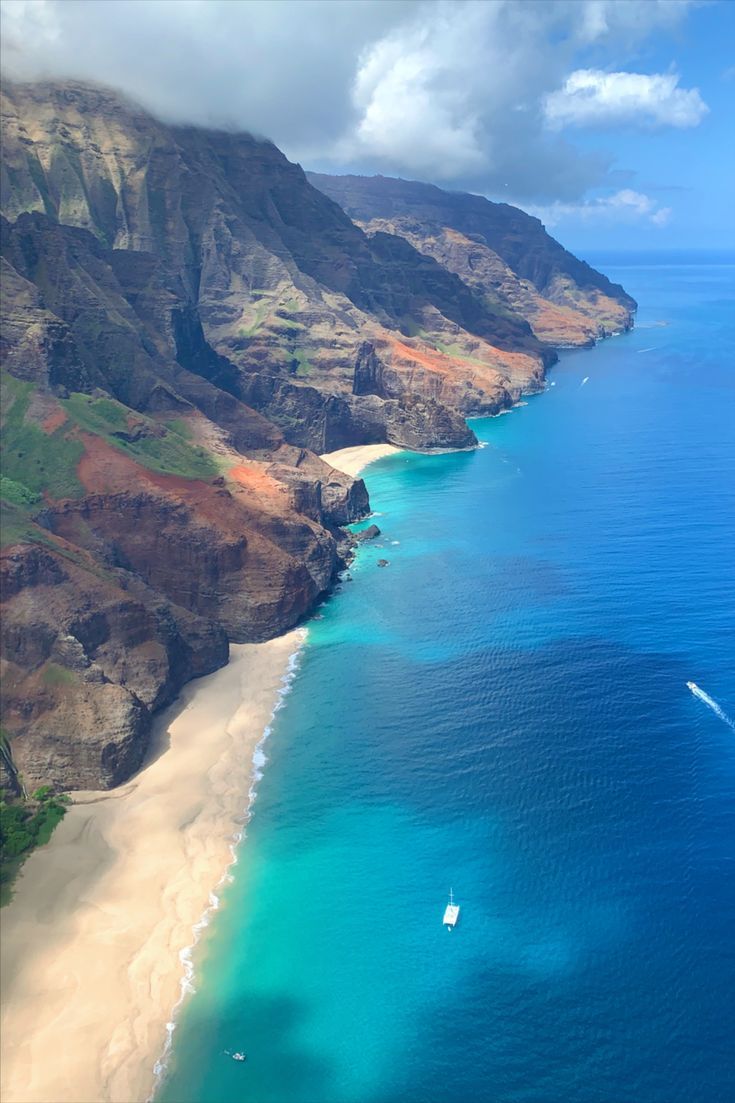 an aerial view of the beach and ocean with boats in the water, near cliffs