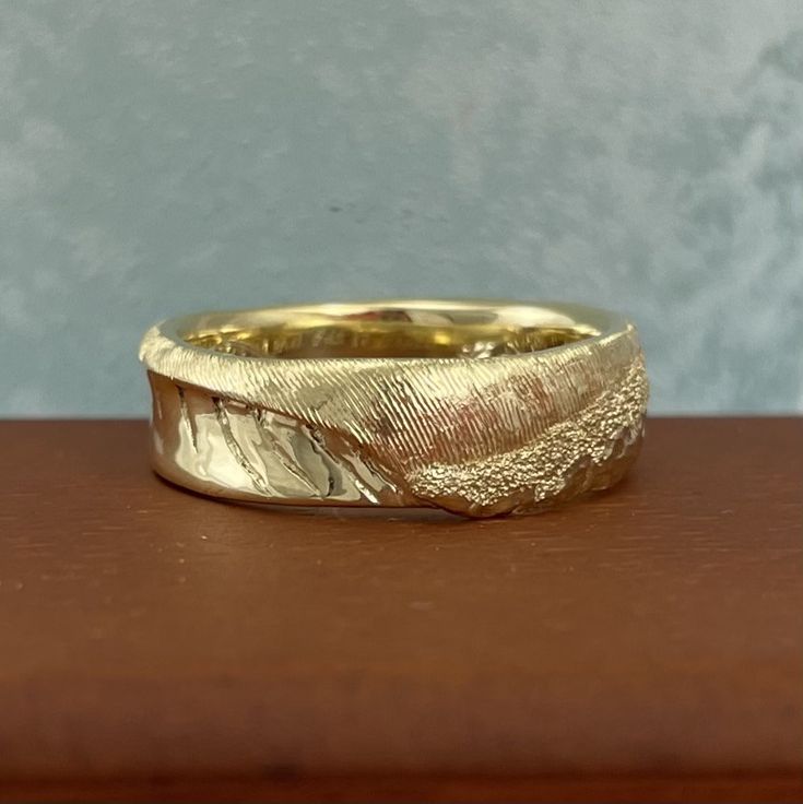 a close up of a gold ring on a wooden surface