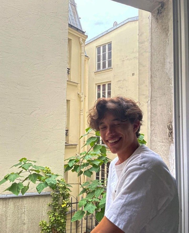 a man standing in front of a window next to a potted plant