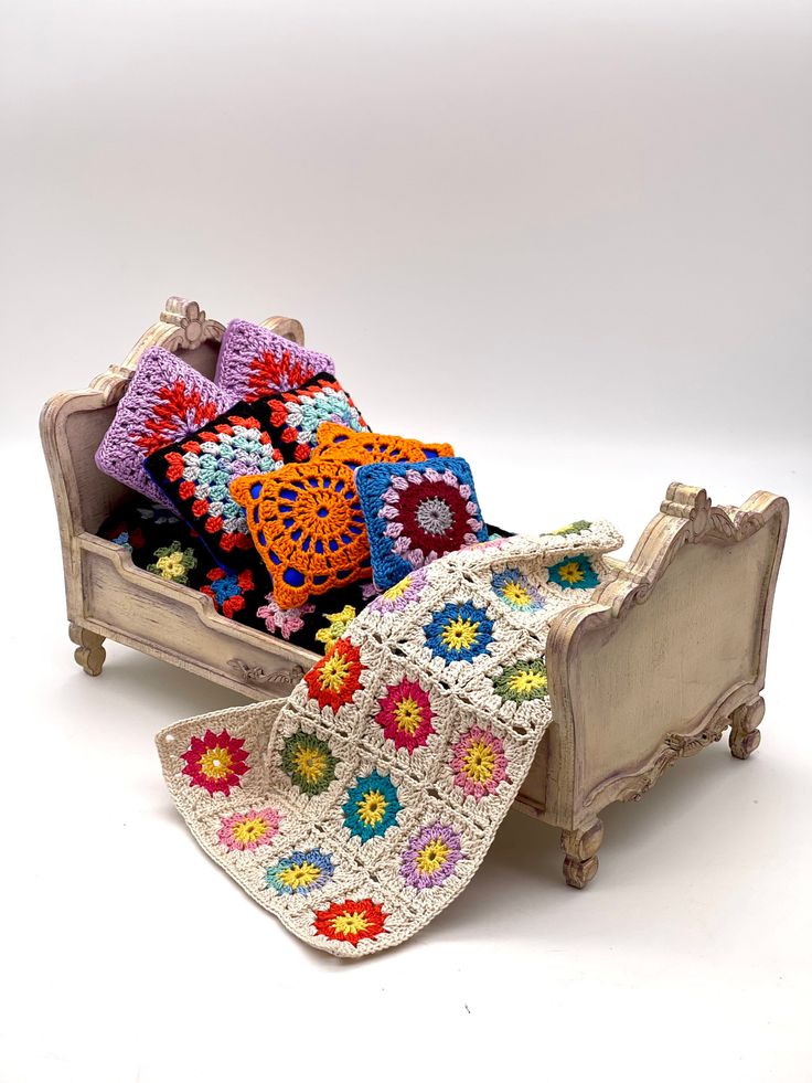 a crocheted blanket is laying on an old wooden bed with white sheets and pillows