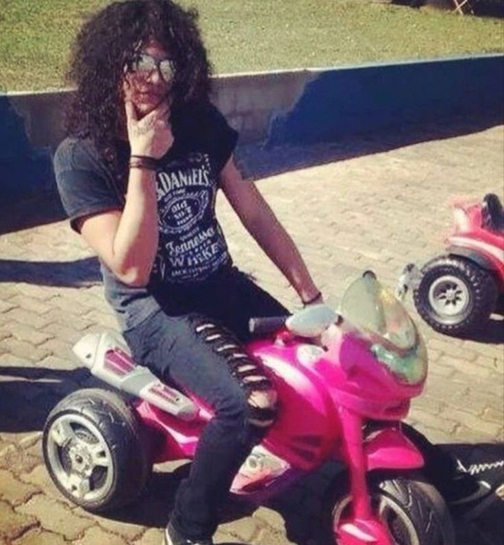 a woman sitting on top of a pink toy motorcycle