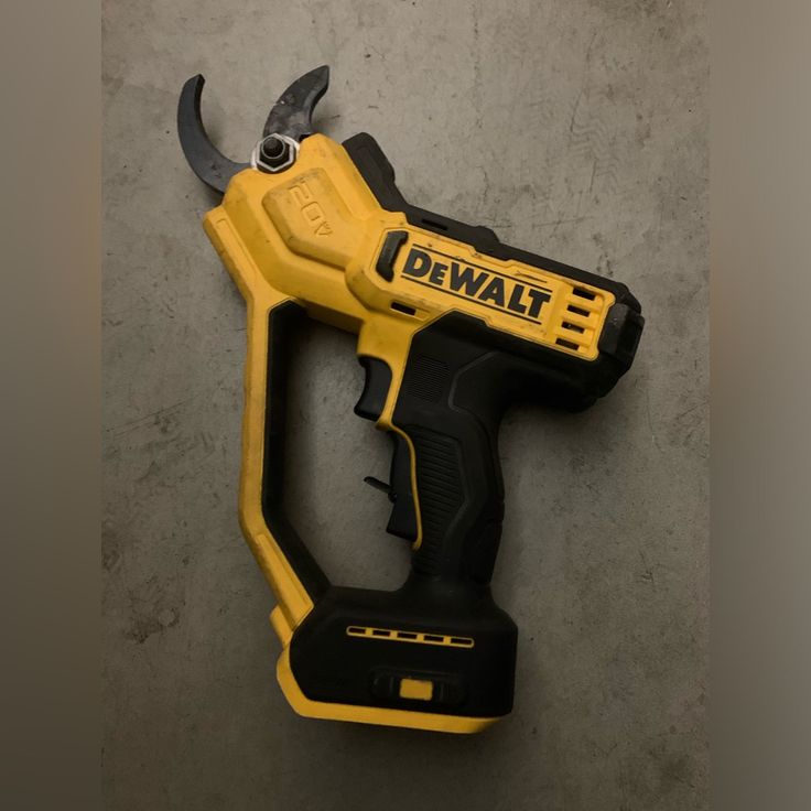 a yellow and black cordless drill is laying on the ground next to a wrench