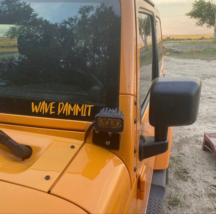 a yellow jeep with the words wave damnit written on it's side window