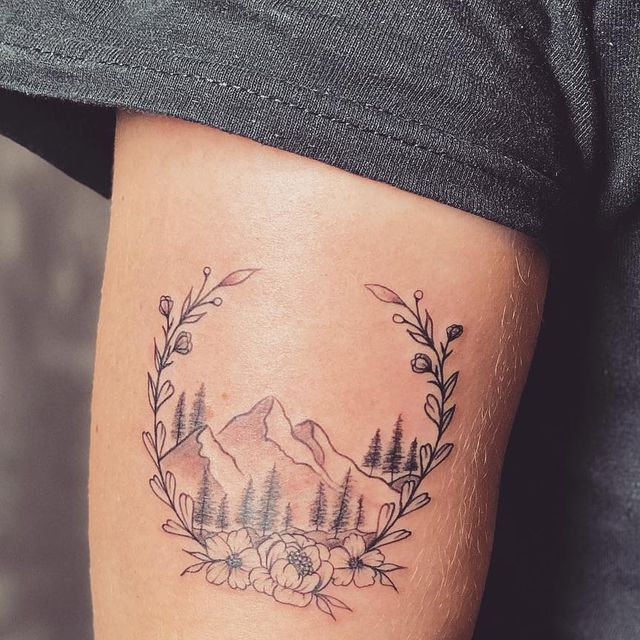 a man with a tattoo on his leg that has trees and mountains in the background