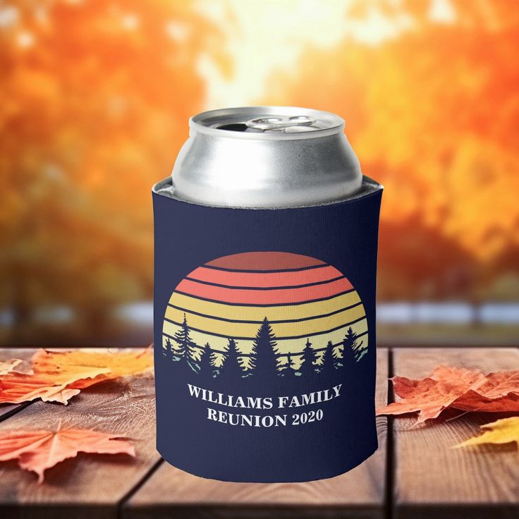 a can cooler sitting on top of a wooden table next to leaves and autumn foliage