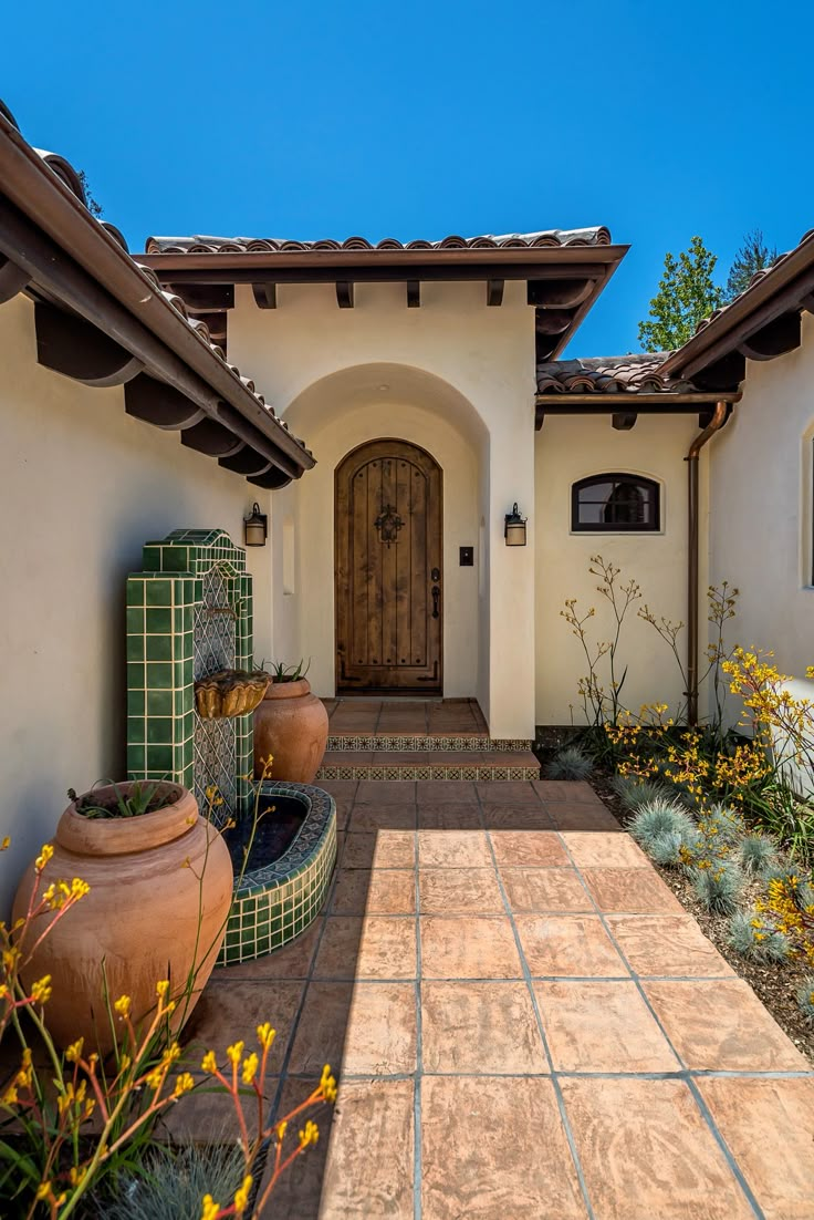 the front entrance to a home with flowers and potted plants