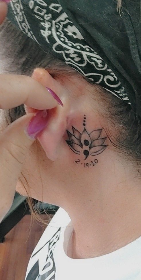 a woman with a flower tattoo on her left side behind the ear, wearing a bandana