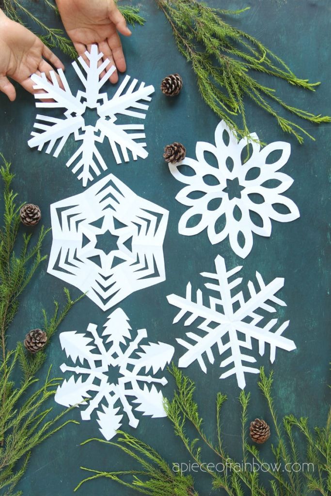 paper snowflakes and pine cones on a table