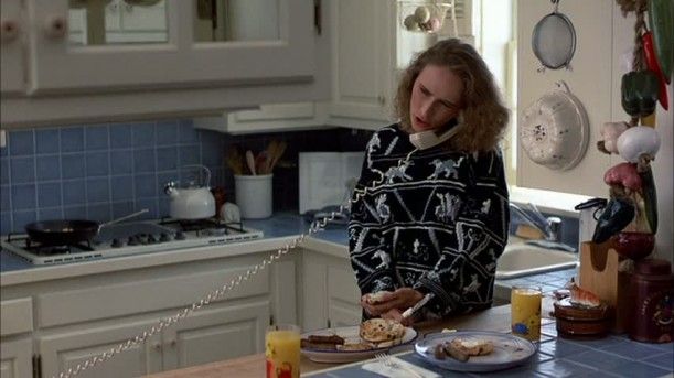 a woman standing in a kitchen with food on the counter and eating from a plate