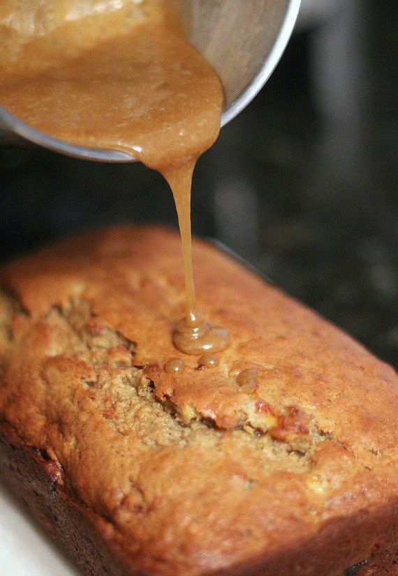 someone pouring peanut butter onto a loaf of bread