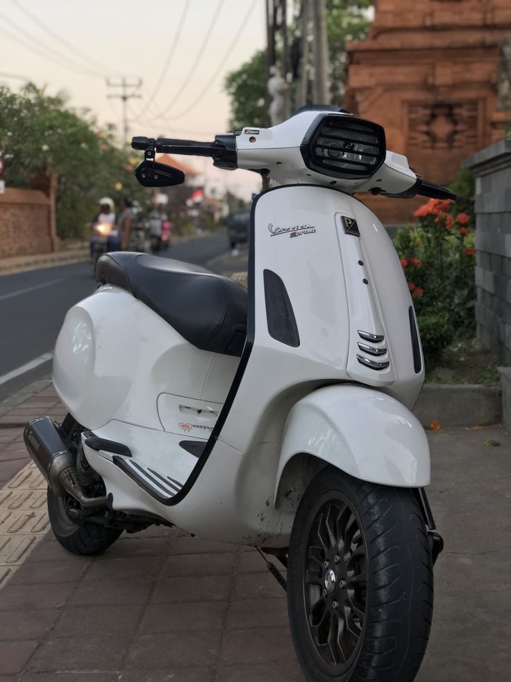 a white scooter is parked on the sidewalk