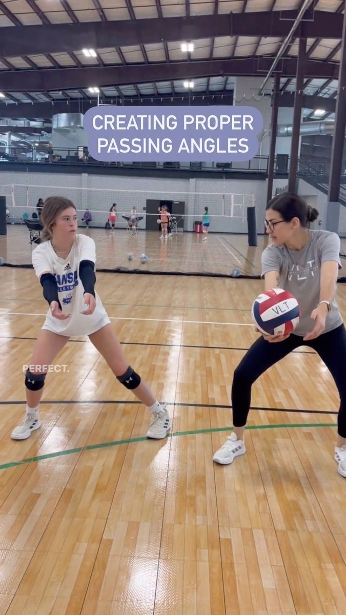 two women are playing volleyball in an indoor gym with wooden floors and hard wood flooring