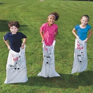 three children standing in the grass holding bags with mickey mouse designs on them and smiling