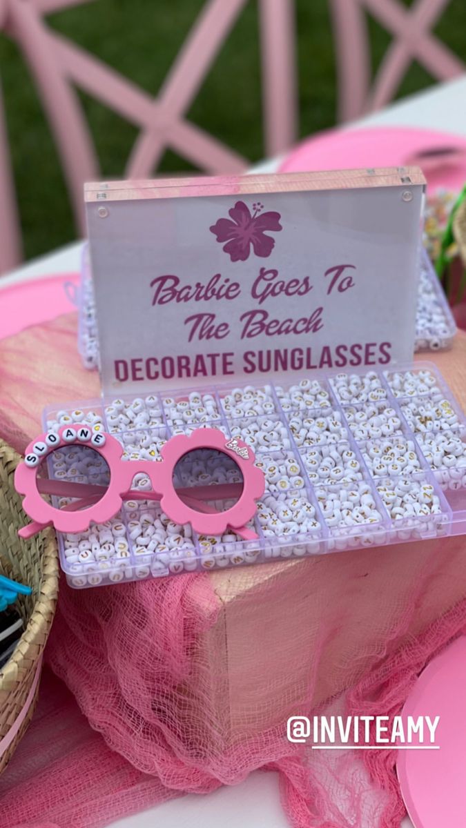 a table topped with pink sunglasses and a sign