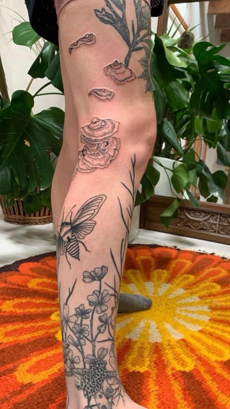 a woman's legs with tattoos on them and flowers in the middle of her leg