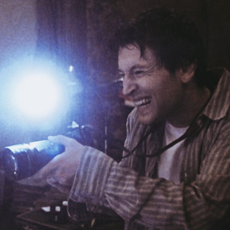 a man smiling while holding a camera in front of his face with a flash light