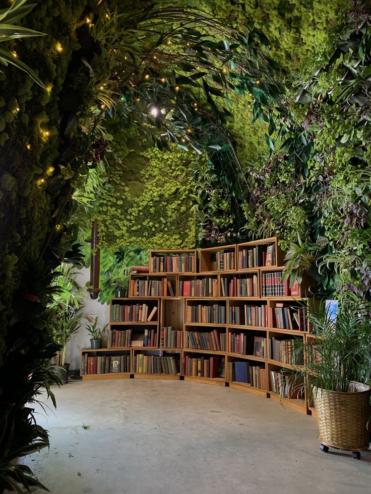 a book shelf filled with lots of books in front of a lush green forest wall